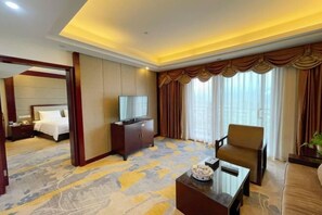 A hotel room with a bed, a TV, a sofa, a coffee table, and a large window with curtains. - XINFANDIAN Hotel (Ganzhou)