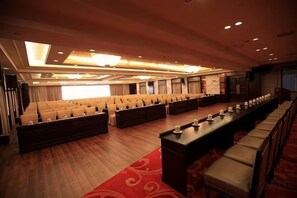 A large conference room with rows of chairs, a long table, and a stage. - XINFANDIAN Hotel (Ganzhou)