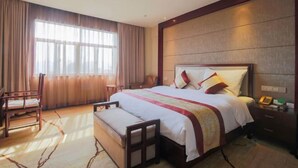 A hotel room with a large bed, a bedside table, a chair, and a window with curtains. - XINFANDIAN Hotel (Ganzhou)