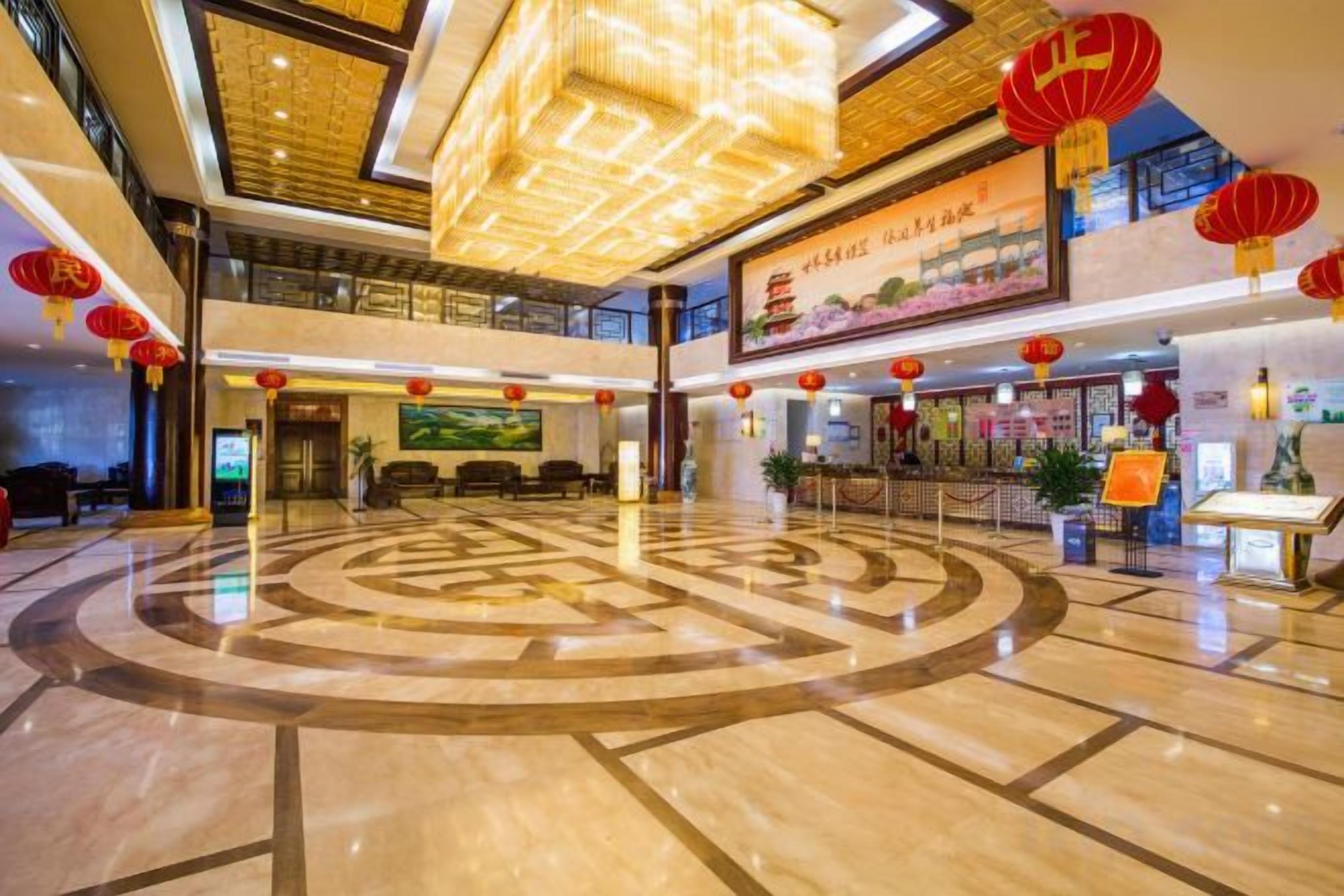 Un vestíbulo de hotel con un diseño circular central en el suelo, una recepción y faroles rojos.