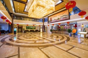 A hotel lobby with a central circular design on the floor, a reception desk, and red lanterns. - XINFANDIAN Hotel (Ganzhou)