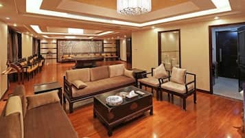 A spacious living area with a sofa set, coffee table, and chairs, a chandelier, and a dining area with chairs and a table.