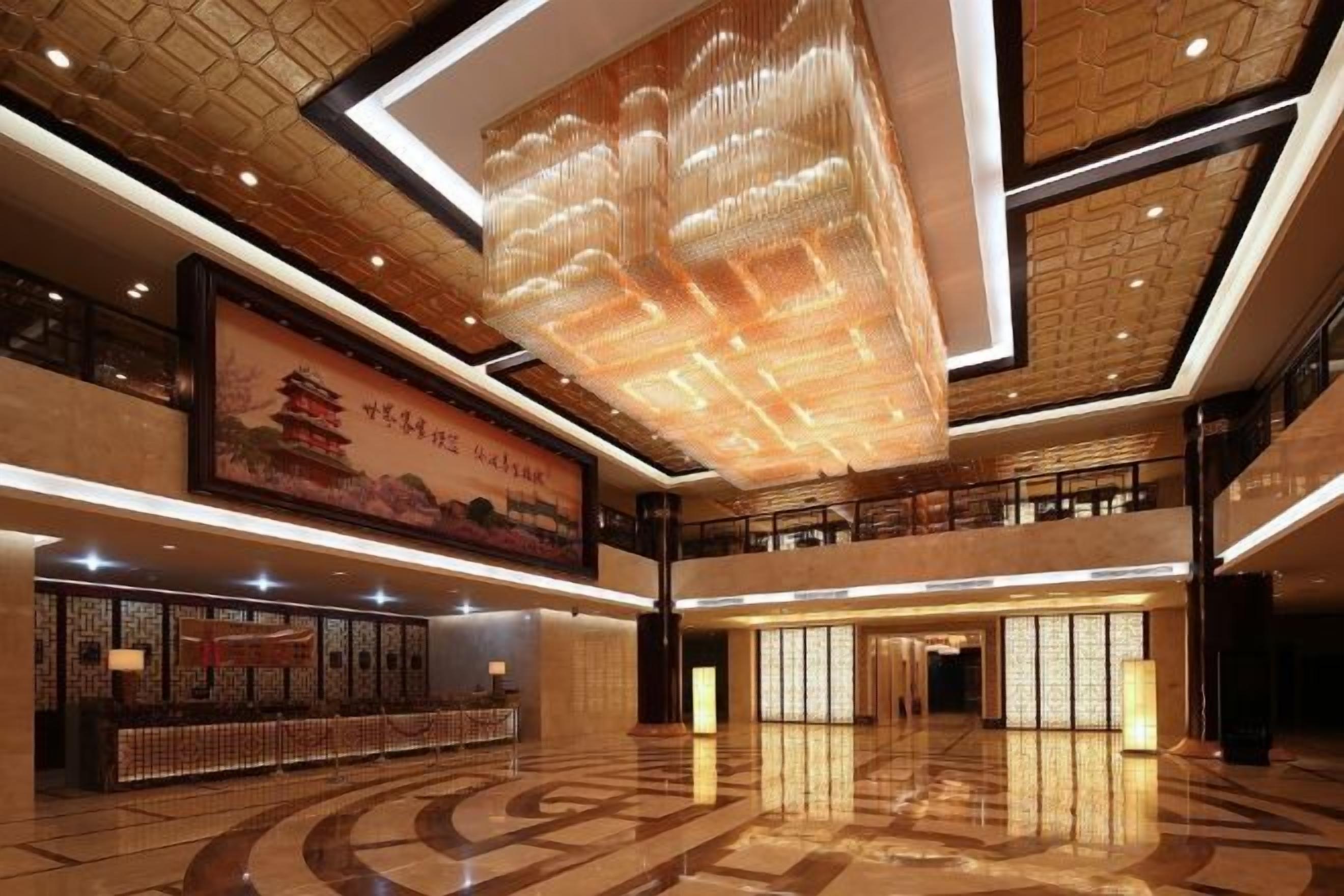 Un vestíbulo amplio con diseño arquitectónico chino tradicional, que incluye un mural grande y un candelabro moderno.