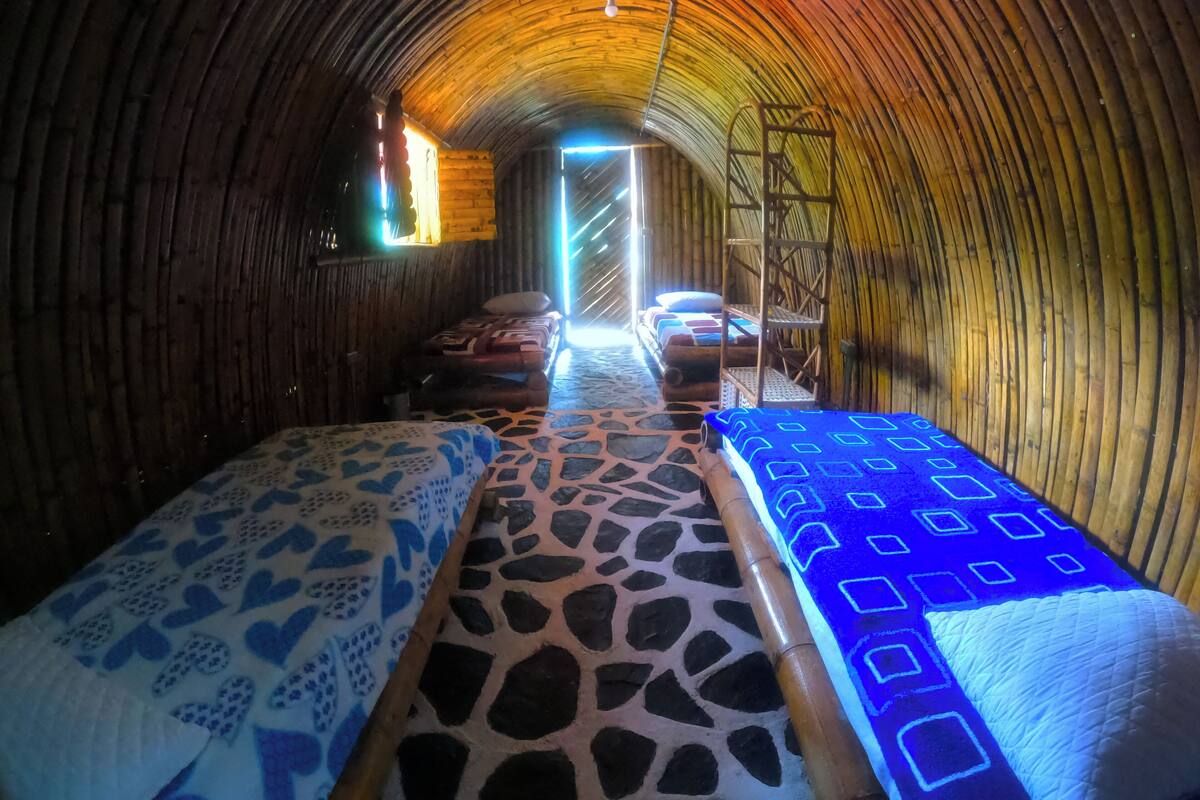 A tunnel-like room with wooden walls, a central stone pathway, and beds with patterned bedding.