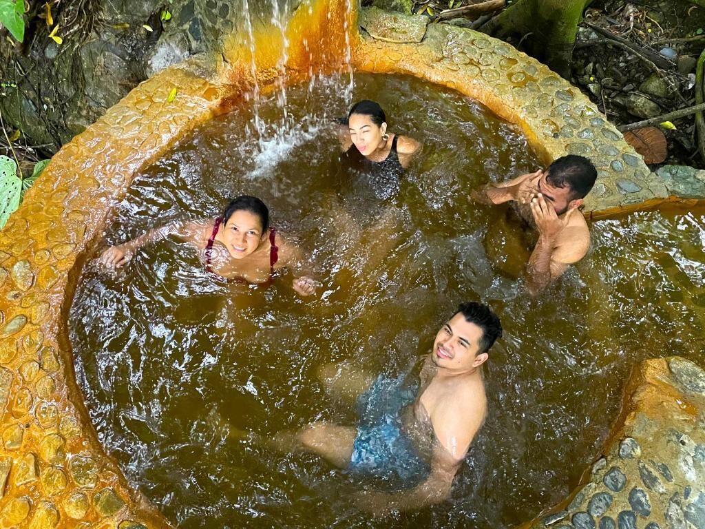 A group of people in a natural water feature with a stone border.