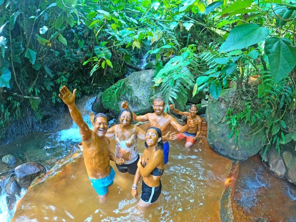 Un grupo de personas disfrutando de una fuente natural rodeada de abundante vegetación.