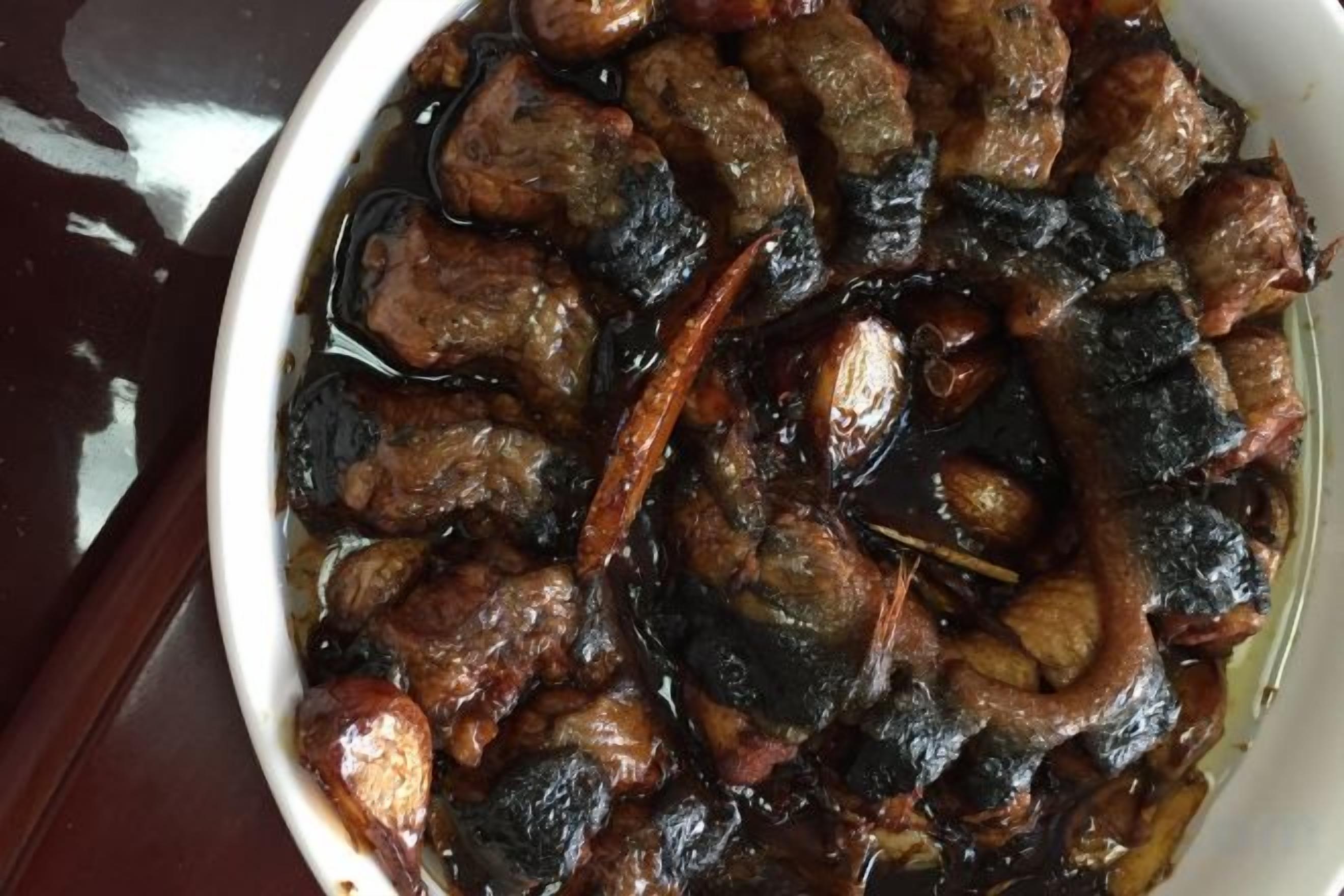 A white bowl filled with a dish of meat and vegetables.