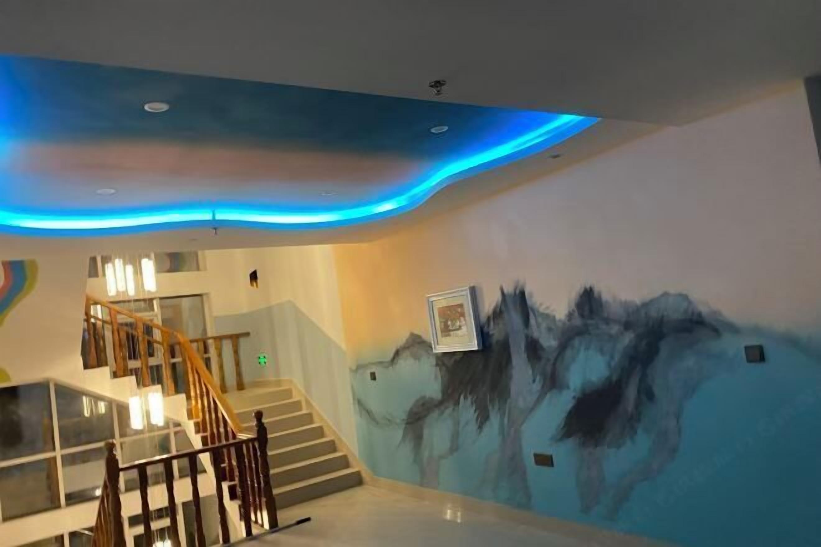 Un interior moderno con una escalera, un mural y una iluminación azul en el techo.