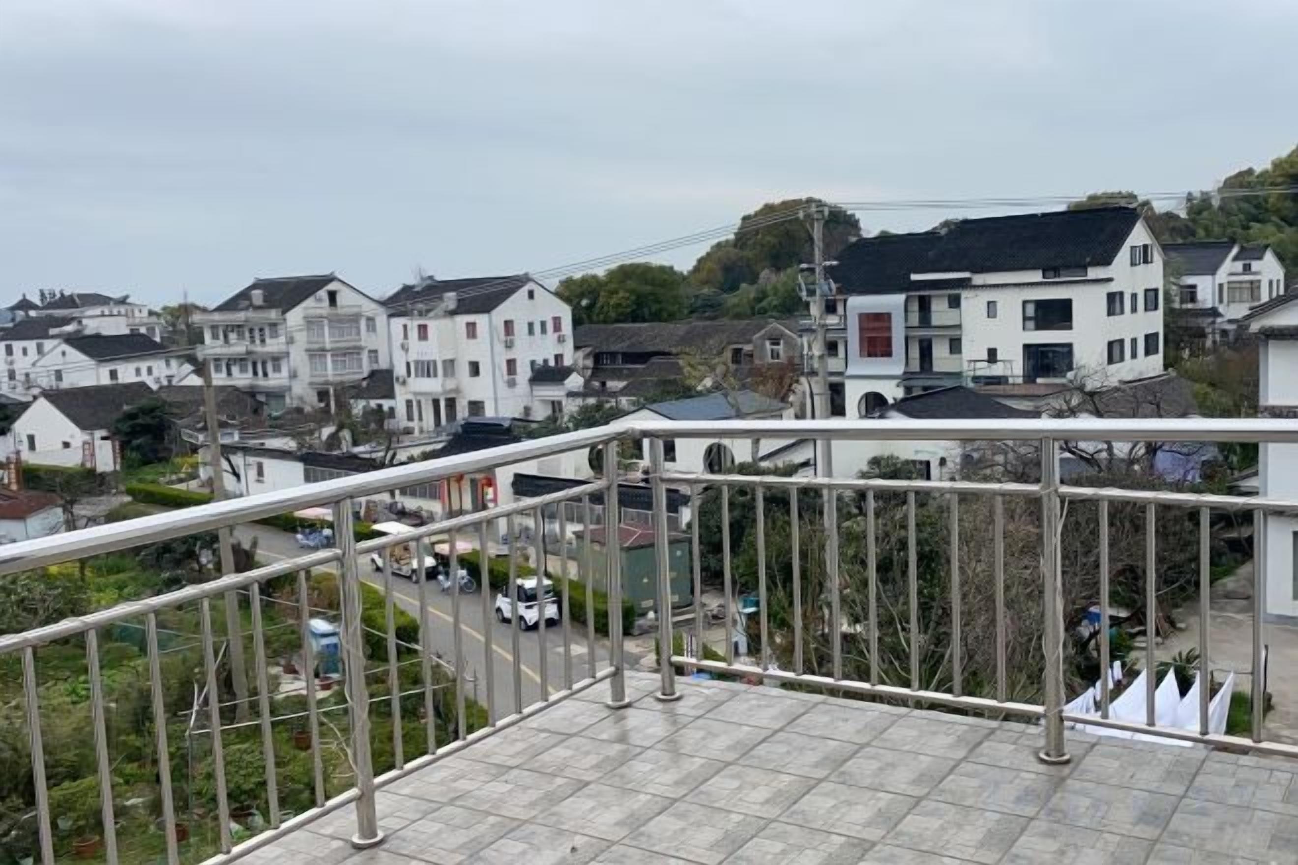 A residential area with houses, a street, and a balcony with a metal railing.
