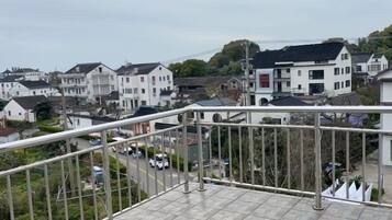 A residential area with houses, a street, and a balcony with a metal railing.