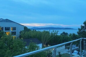 A modern building with a balcony overlooking a body of water and distant mountains. - Sanshan Island Bee Cai Homestay (Suzhou)
