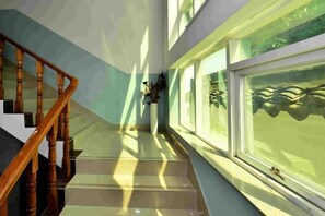 A staircase with wooden handrails leading to a landing with a window. - Sanshan Island Bee Cai Homestay (Suzhou)