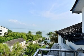 A traditional building with a tiled roof overlooking a body of water and greenery. - Sanshan Island Bee Cai Homestay (Suzhou)