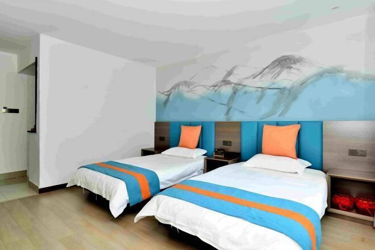 Ein Hotelzimmer mit zwei Betten, einem großen, abstrakten Gemälde an der Wand und Holzboden.