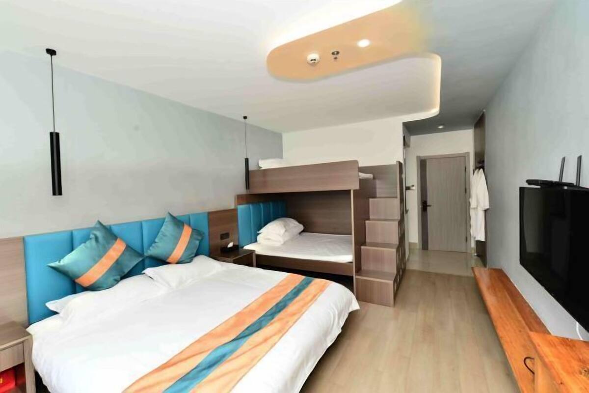 Ein Hotelzimmer mit Etagenbett, Flachbildfernseher, Nachttisch und einer Holzbank.