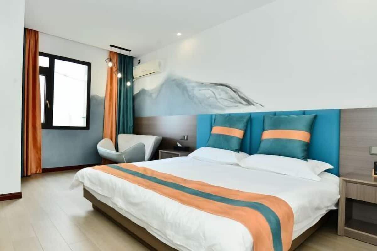 Ein Hotelzimmer mit Bett, Stuhl, Nachttisch und Wandbild.