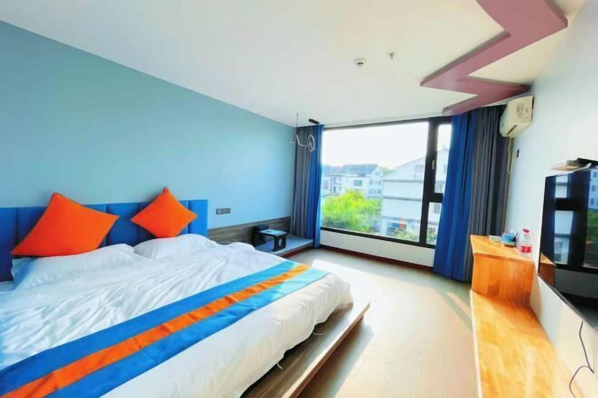 Ein Hotelzimmer mit Bett, Fernseher, Schreibtisch und großem Fenster.