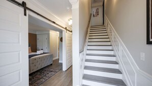 A staircase leading to a bedroom with a bed and a rug.