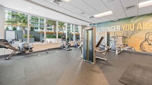 Una palestra con attrezzature per esercizi, ampie finestre e un murale motivazionale.