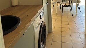 Ein Waschbereich mit Waschmaschine, Holztisch und Esstisch mit Stühlen.