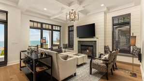 A modern living room with a fireplace, large windows, and a view of the ocean. - Michigan Shores / Lake View, Pool & Game Room (South Haven)