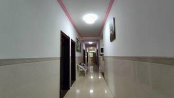 A corridor with a tiled floor, a ceiling light, and a door on the left.