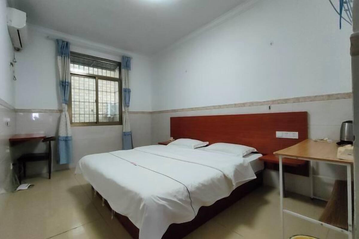 A room with a bed, a desk, and a window with curtains.