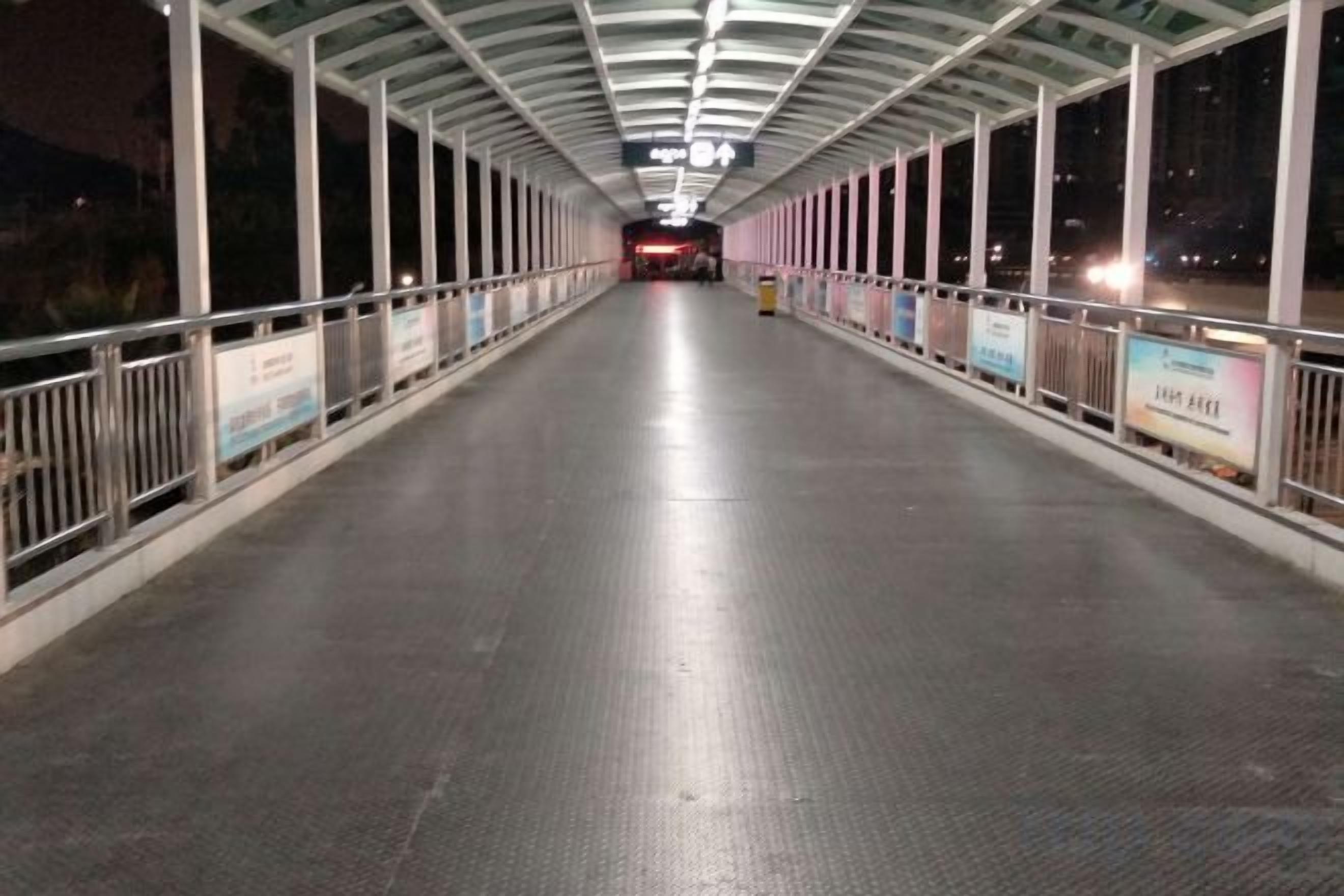 Un pont piétonnier couvert, doté de garde-corps et de panneaux indicateurs.
