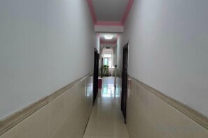 Un pasillo con piso de baldosas y paredes blancas, que conduce a una puerta al final.