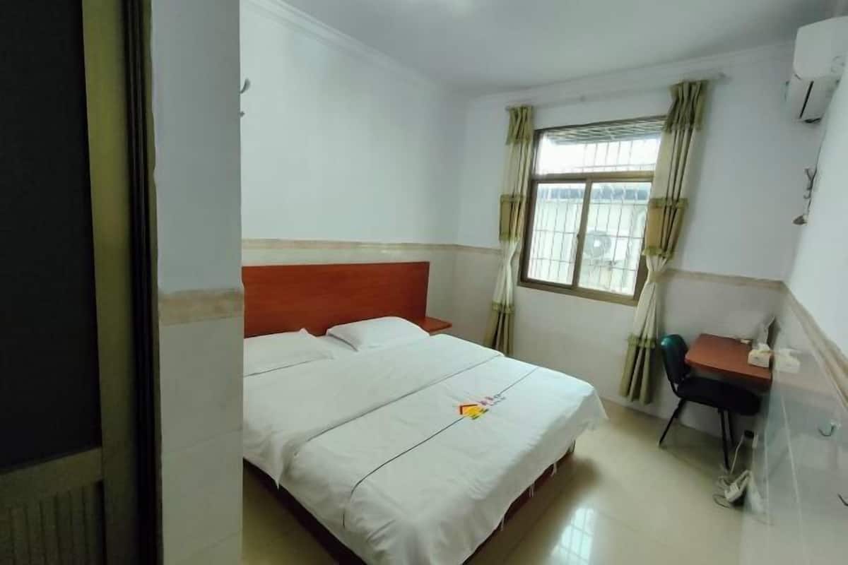 A hotel room with a bed, a desk, and a window with curtains.