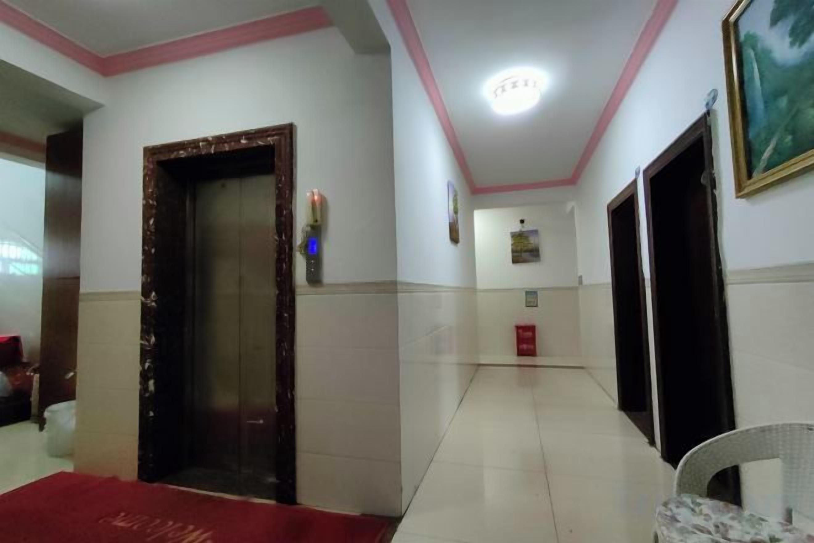 Ein Hotelkorridor mit rotem Teppich, einer Tür, einer Wandleuchte und einem gerahmten Bild.