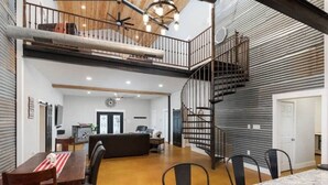 A spacious living area with a dining table, chairs, a sofa, and a staircase.