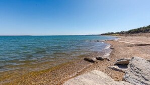 A beach with clear water, pebbles, and rocks.