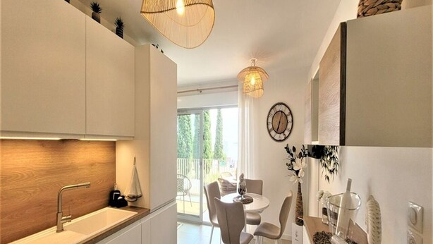 A modern kitchen with a built-in sink, a dining area with a round table and chairs, and a view of the outdoors.