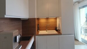 A modern kitchen with white cabinets, a wooden countertop, and a built-in sink.