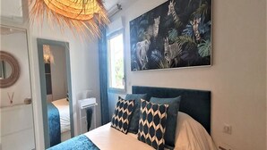 A bedroom with a bed, a large painting of animals, and a window.