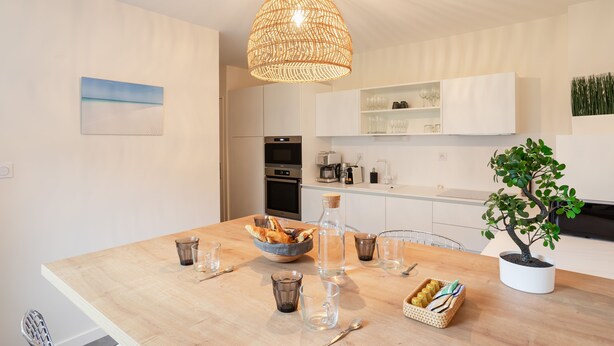 A modern kitchen with a wooden table, a hanging light fixture, and a potted plant. - La Petite Maison Dans la Prairie - Havre de paix (Rennes)