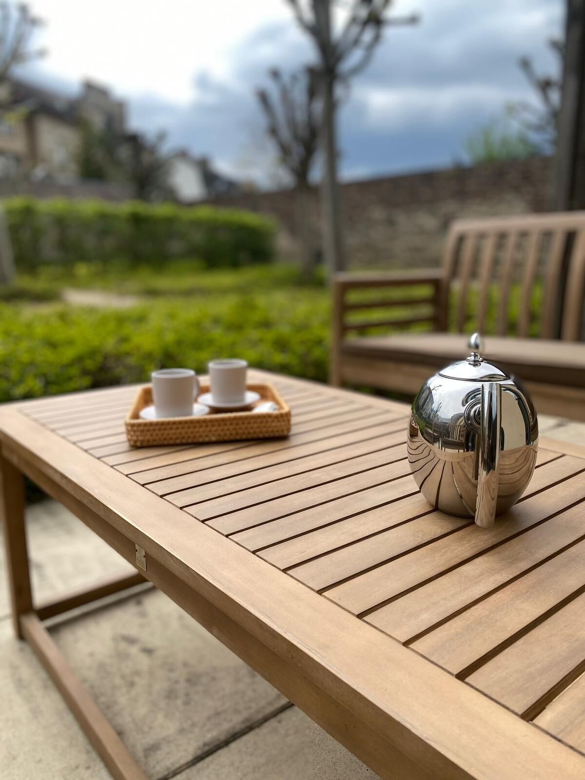 Een houten tafel met een theepot en kopjes op een dienblad.