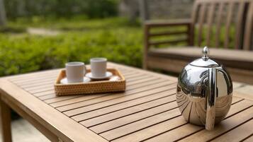 Een houten tafel met een theepot en kopjes op een dienblad.