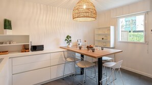 A modern kitchen with a wooden island, white cabinetry, and a hanging light fixture. - La Petite Maison Dans la Prairie - Havre de paix (Rennes)