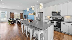 A modern kitchen with white cabinets, stainless steel appliances, and a central island with bar stools. - Rooftop Views! Luxury East Nash 3 BR Townehome (Nashville)