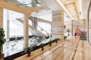 Un hall amplio con una fuente de agua, plantas en macetas y una escalera.