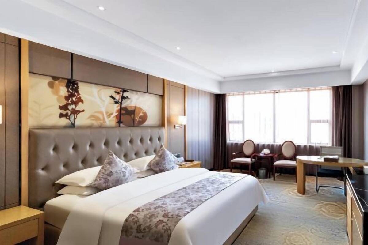 A hotel room with a large bed, a desk, and a chair.