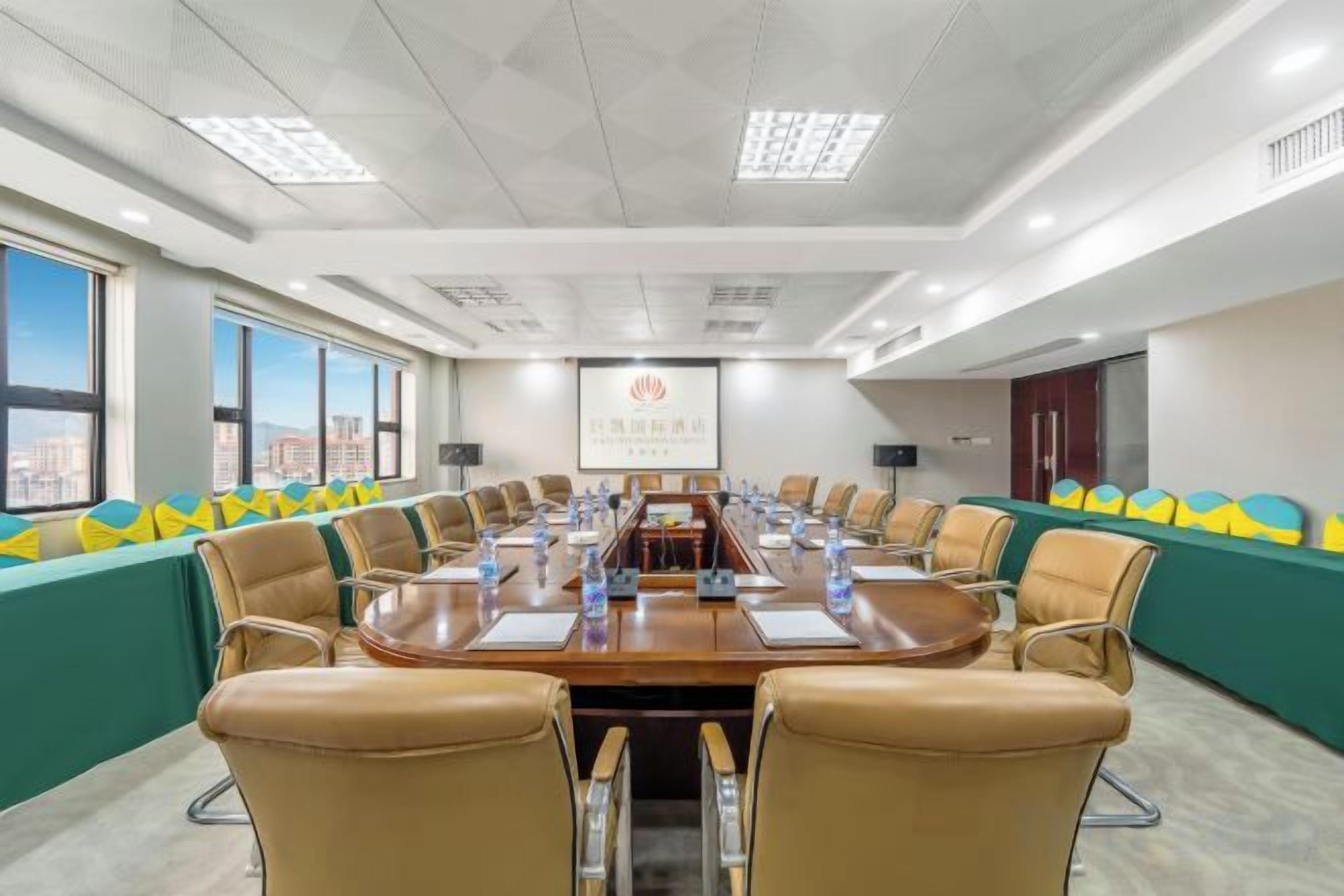 A conference room with a long table, chairs, and a projector screen.