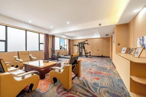 Een hotelkamer met een groot raam, een bank, een bureau en trainingsapparatuur.