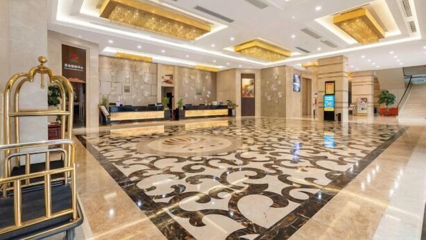 Een hotel lobby met een receptiebalie, een groot patroon vloer en een modern plafondontwerp.