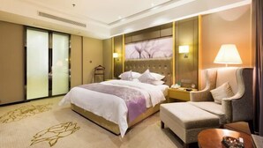 Een hotelkamer met een bed, een stoel, een nachtkastje en een lamp.