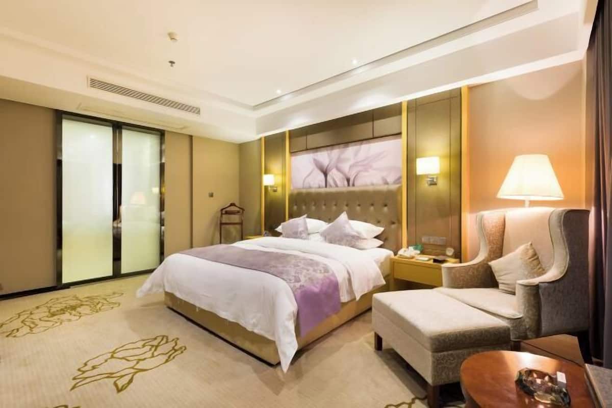 A hotel room with a bed, a chair, a nightstand, and a lamp.