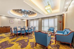A hotel room with a dining area, a sofa, a chandelier, and a large window. - Jukai International Hotel (Nan'an)