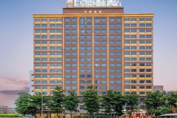Un edificio de hotel de varios pisos con fachada uniforme, una serie de ventanas y un letrero llamativo en la parte superior.